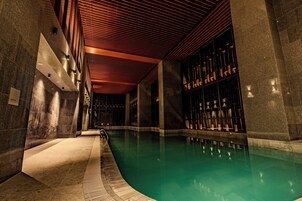 Una piscina con suelo de baldosas y techo de madera.