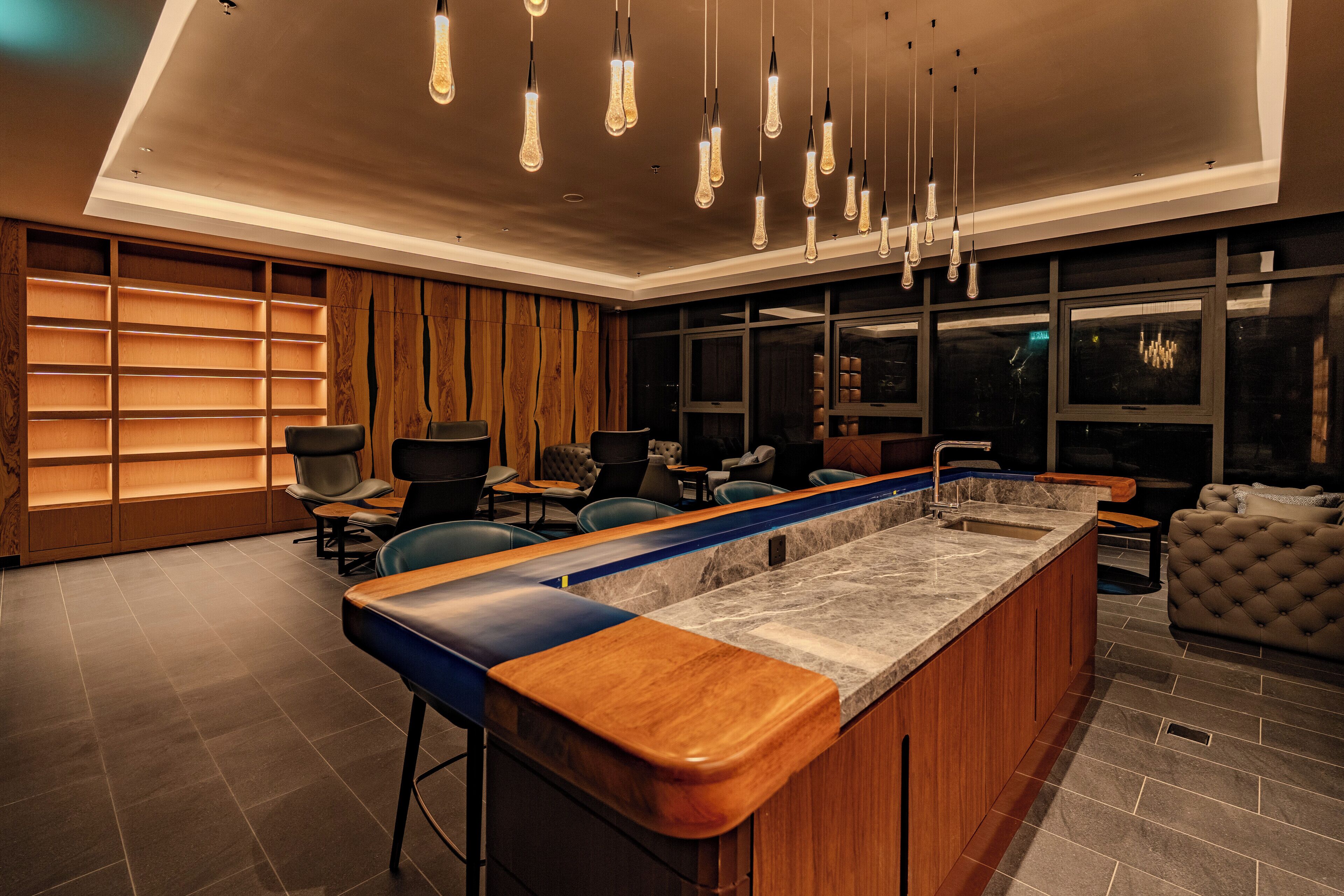 Eine moderne Bar mit einer langen Theke, Sitzplätzen und Pendelleuchten.