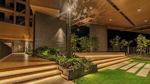 A modern building with a wooden ceiling, outdoor steps, and green landscaping.