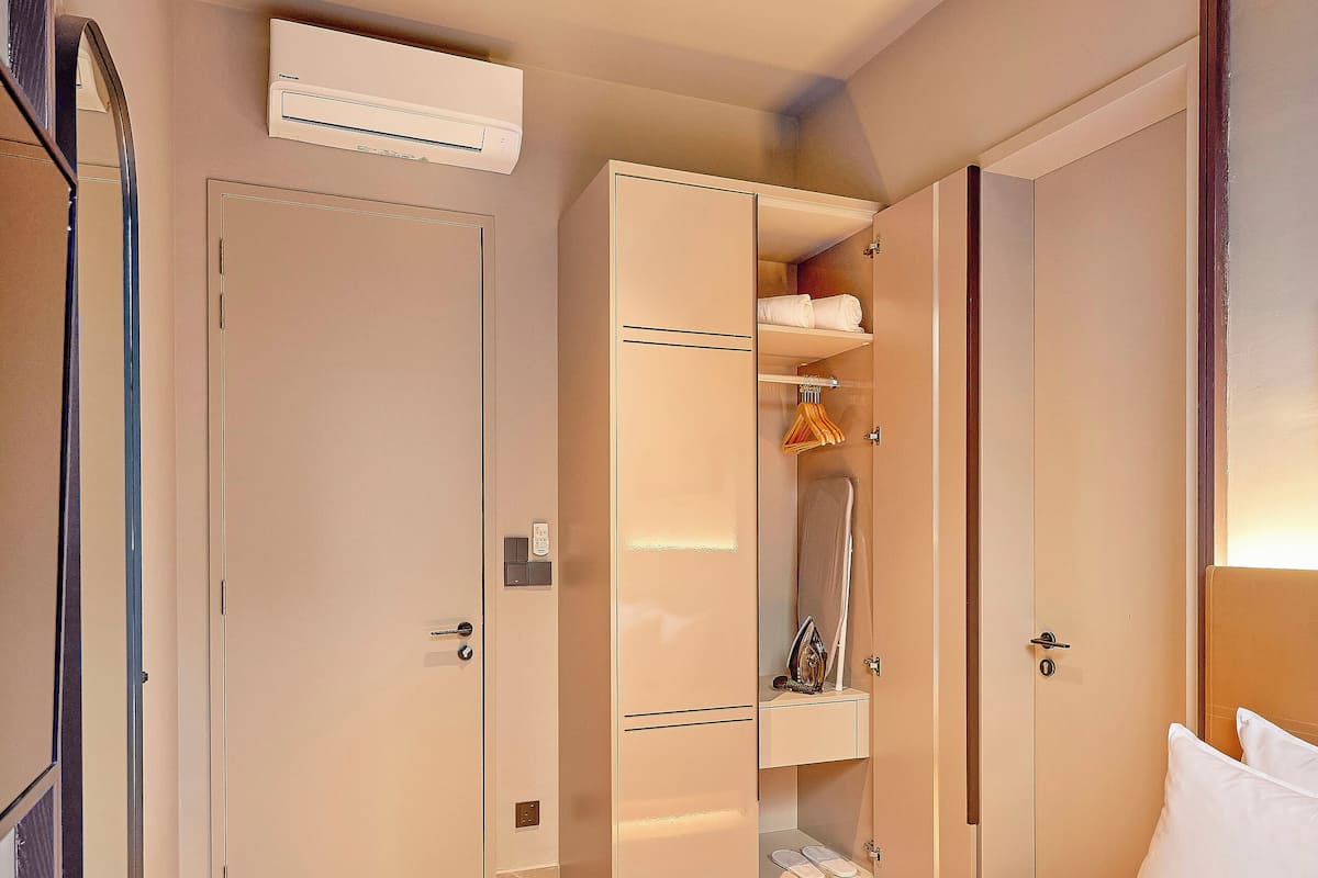 Una habitación de hotel con cama, armario y aire acondicionado.