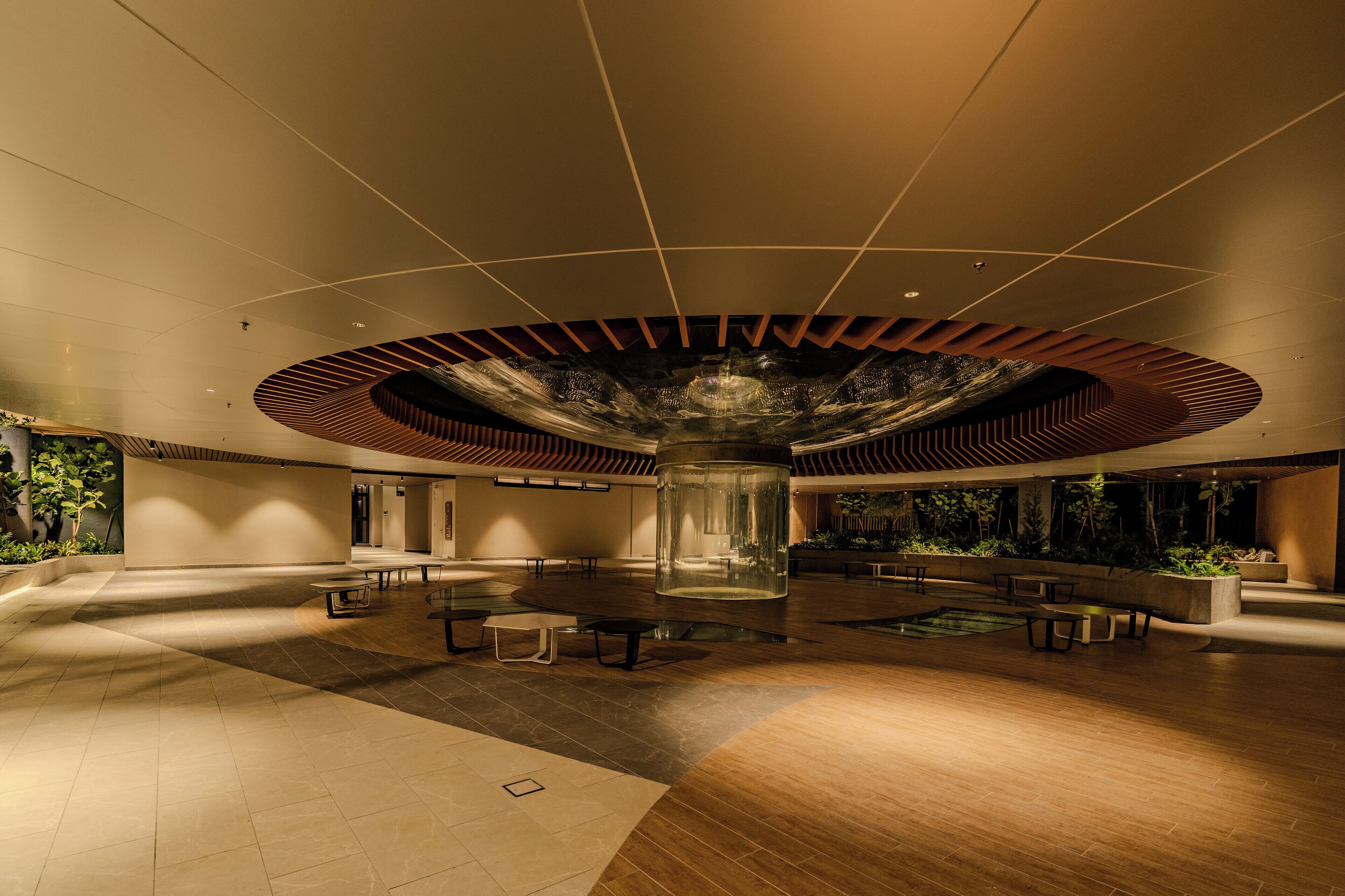 A spacious indoor area with a central column, seating arrangements, and a ceiling with a unique design.