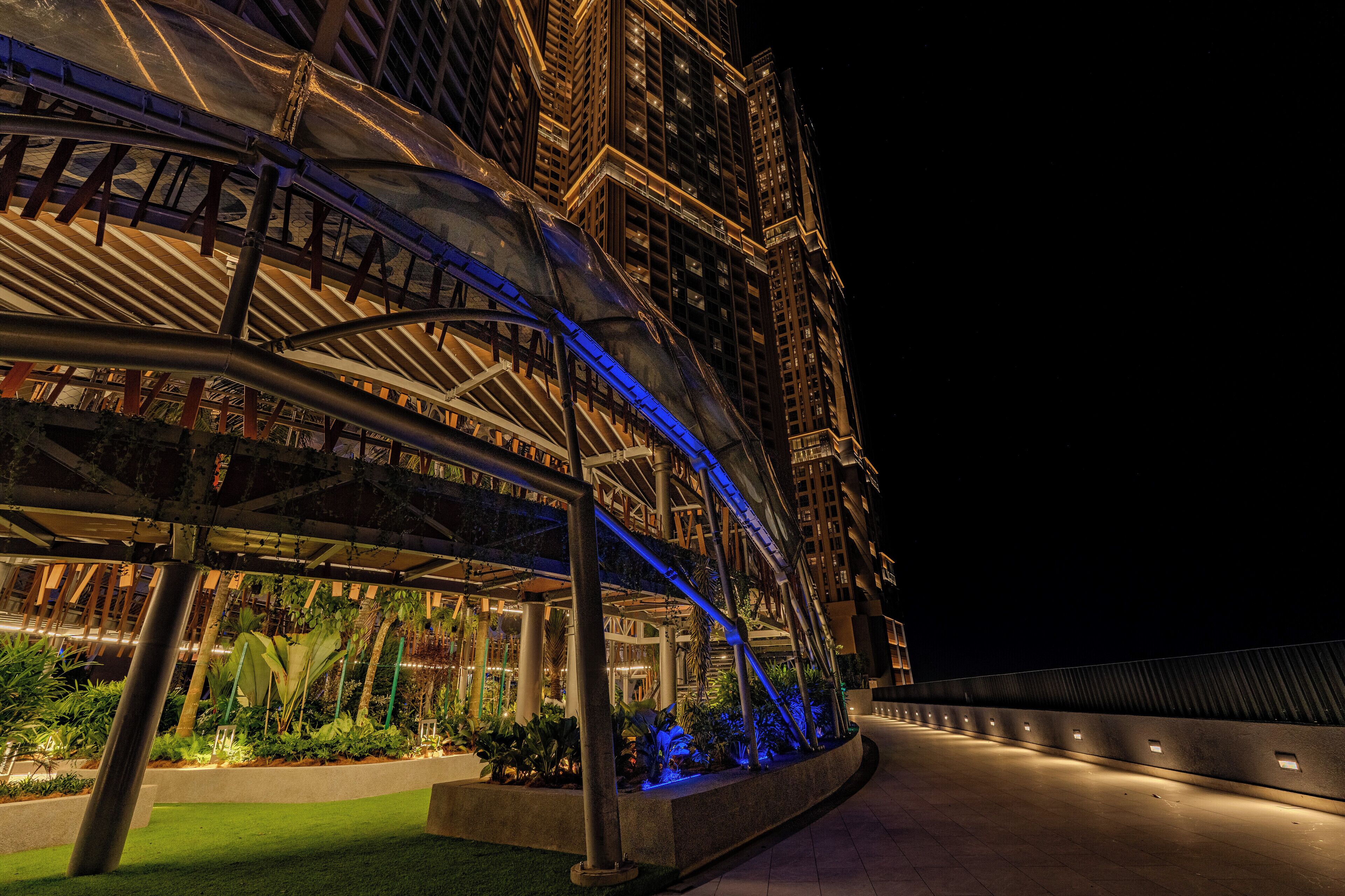 A modern building with a covered outdoor area, featuring structural beams and a pathway.
