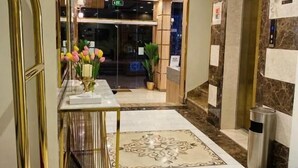 A hotel lobby with a marble floor, a reception desk with a vase of flowers, a staircase, and an elevator. - Mayar Golden Hotel (Madinah)