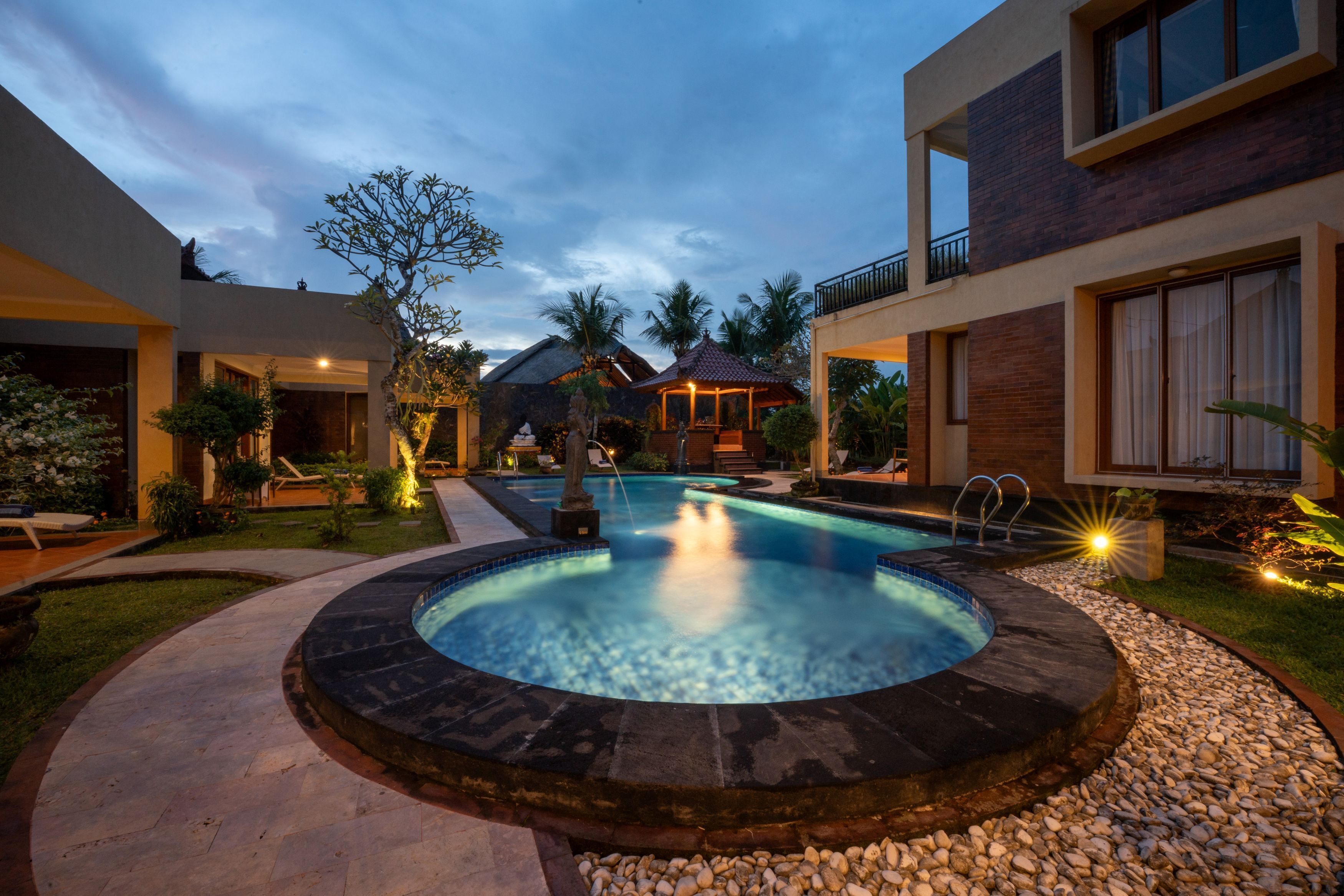 A modern hotel with a swimming pool, outdoor seating, and a well-maintained garden.