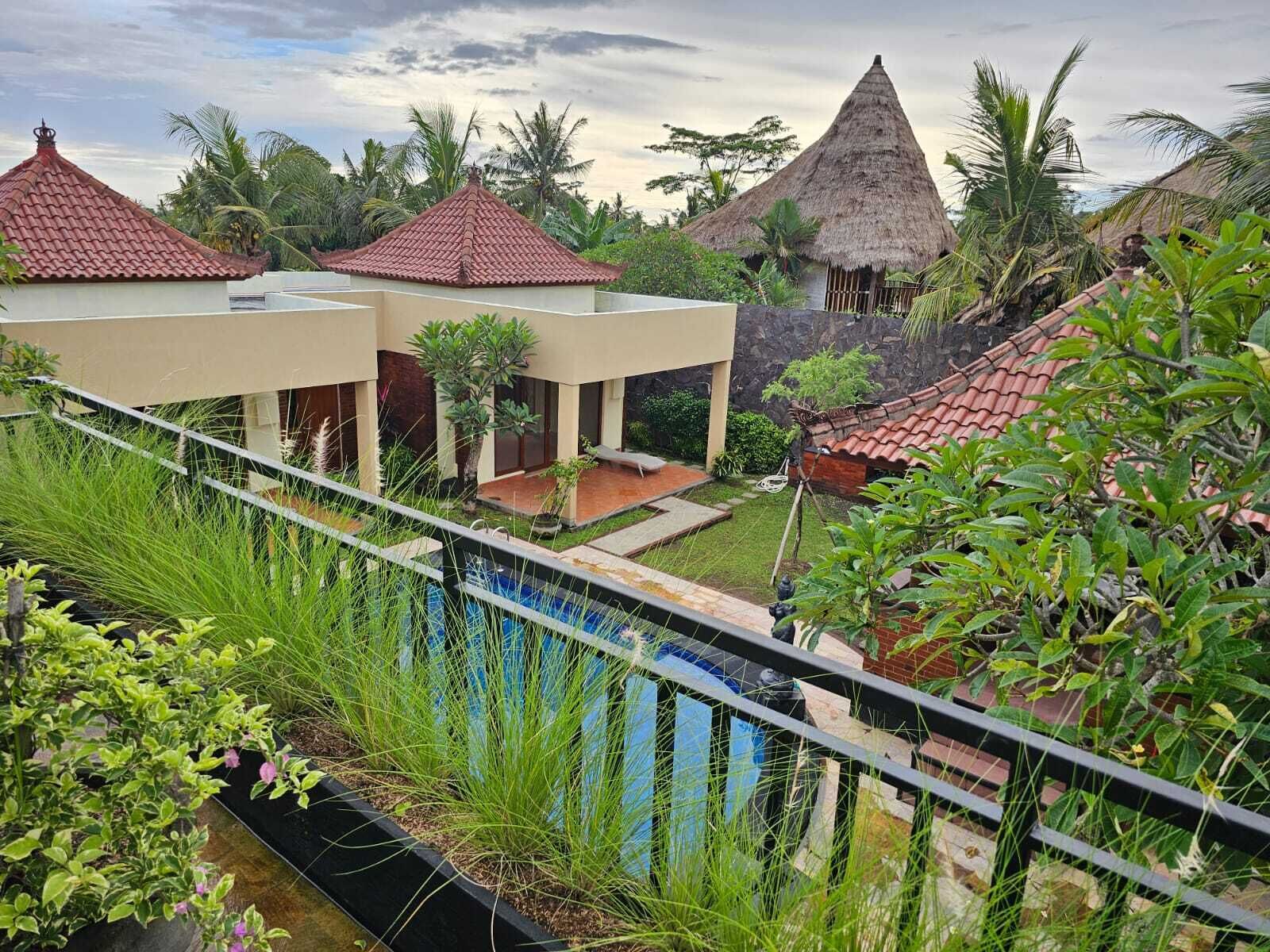 Un resort con varias edificaciones, piscina y exuberante vegetación.