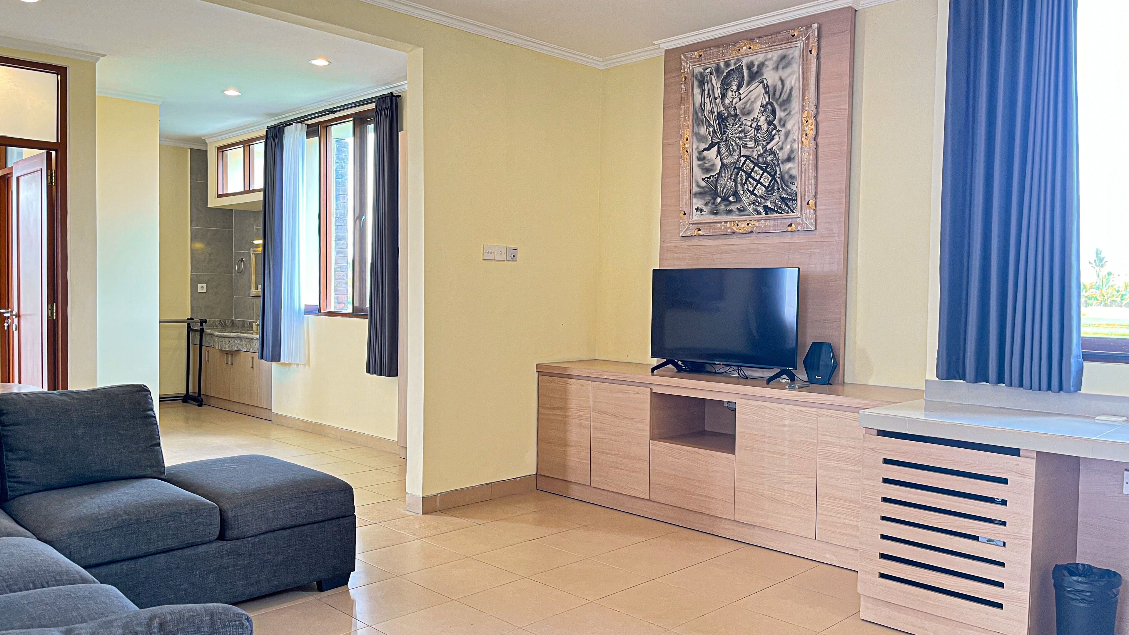 Uma sala de estar moderna com televisão de tela plana, armários de madeira e um sofá cinza.