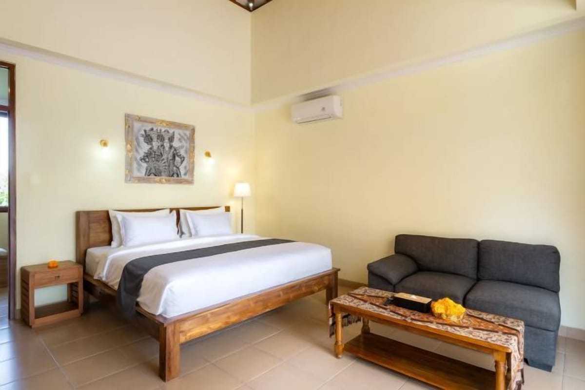 A bedroom with a bed, bedside tables, a sofa, and a small table.