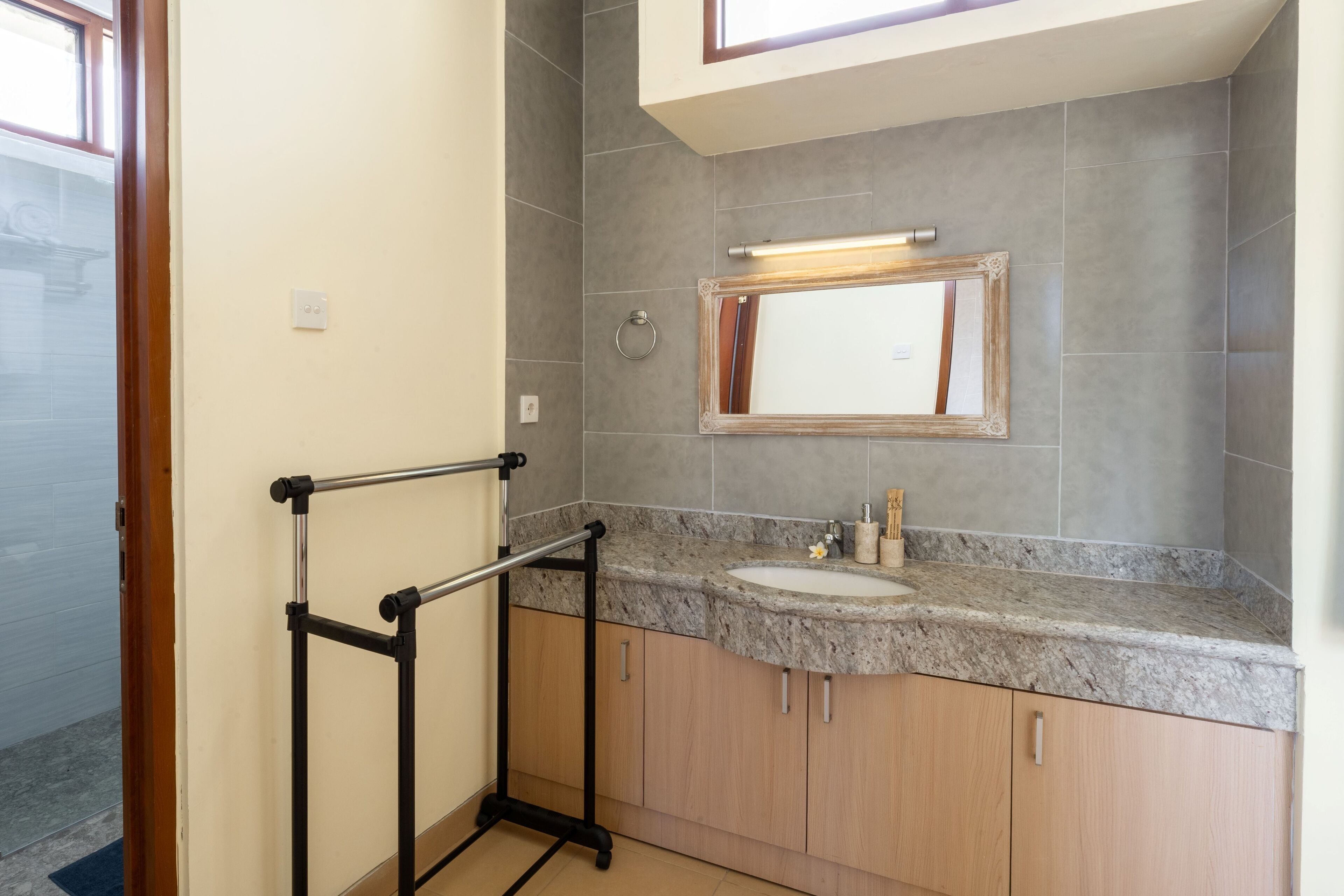 A bathroom with a granite countertop, a sink, a mirror, and a towel rack.