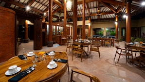 Un vaste espace dédié à la salle à manger, avec de hautes poutres en bois, de nombreuses tables dressées et une grande fresque murale.