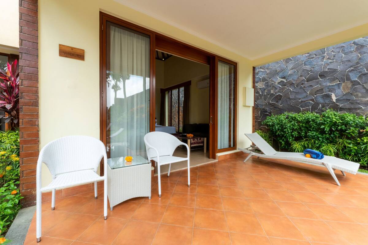 Un balcón con mobiliario de mimbre blanco, una pared de piedra y vistas al interior.