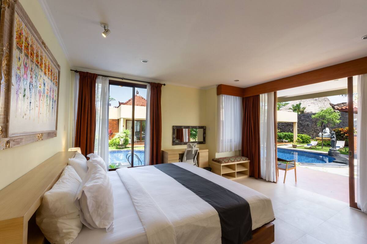 Habitación de hotel con una cama grande, un escritorio, una silla y vista a una piscina.