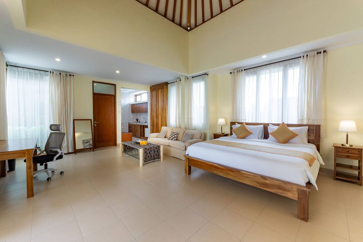 Amplia habitación de hotel con una cama grande, un sofá, un escritorio y una kitchenette.