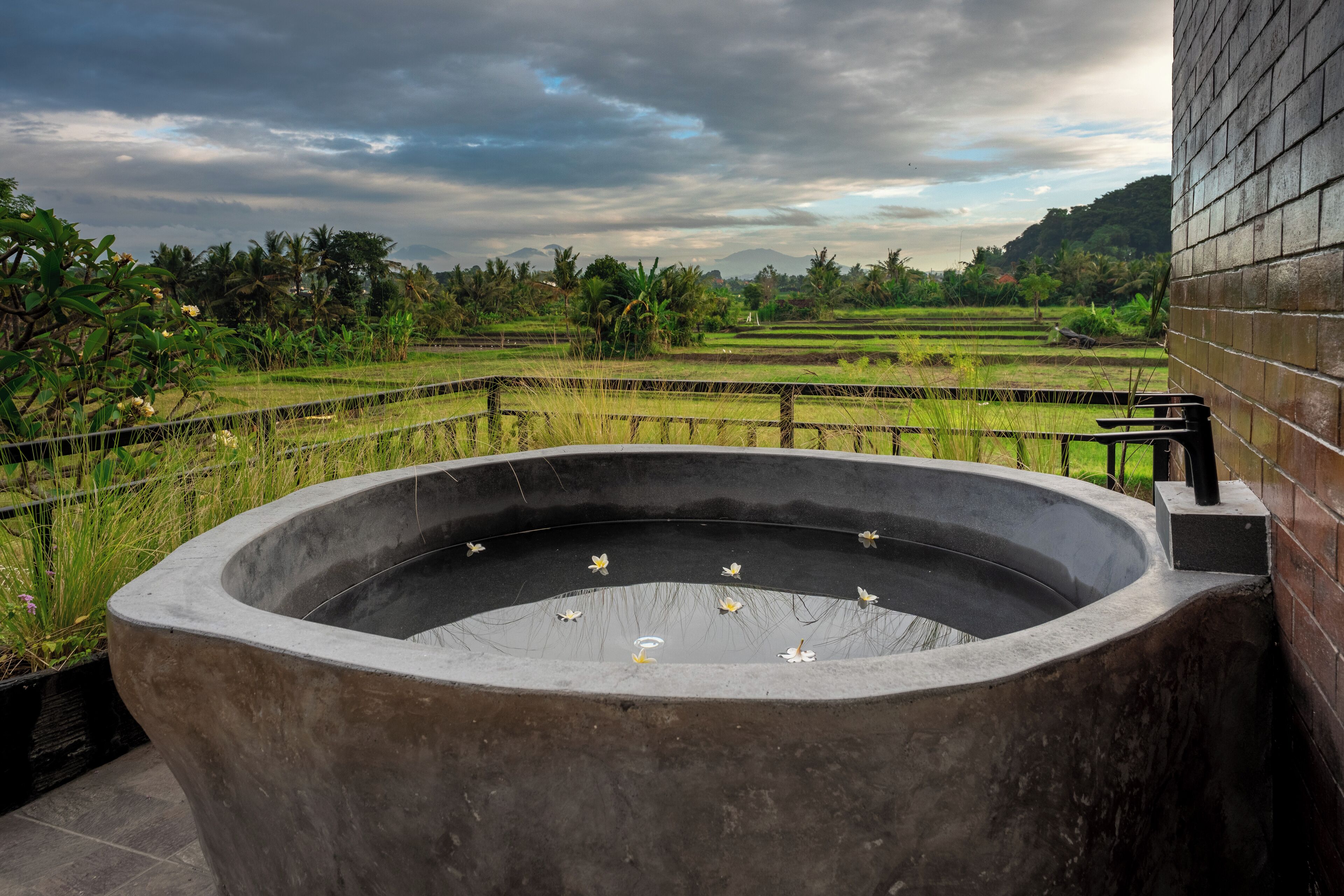 A large concrete water feature with a view of a lush landscape and distant mountains.