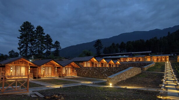 A row of wooden cabins with large windows and a stone staircase leading up to a covered area. - Gangtey Pinewood Resort (Wangdue Phodrang)