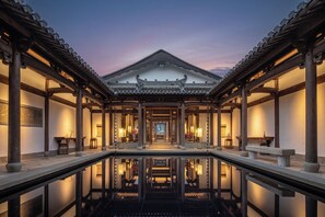 Un edificio tradicional con un patio central y una piscina reflectante.
