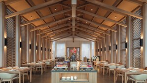 A spacious dining area with wooden beams and lattice partitions, featuring a central buffet with various food items. - Huangshan Misty Rain Resort Hotel (Huangshan)