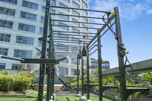 A gym with a metal frame structure, outdoor exercise balls, and a green artificial turf area.