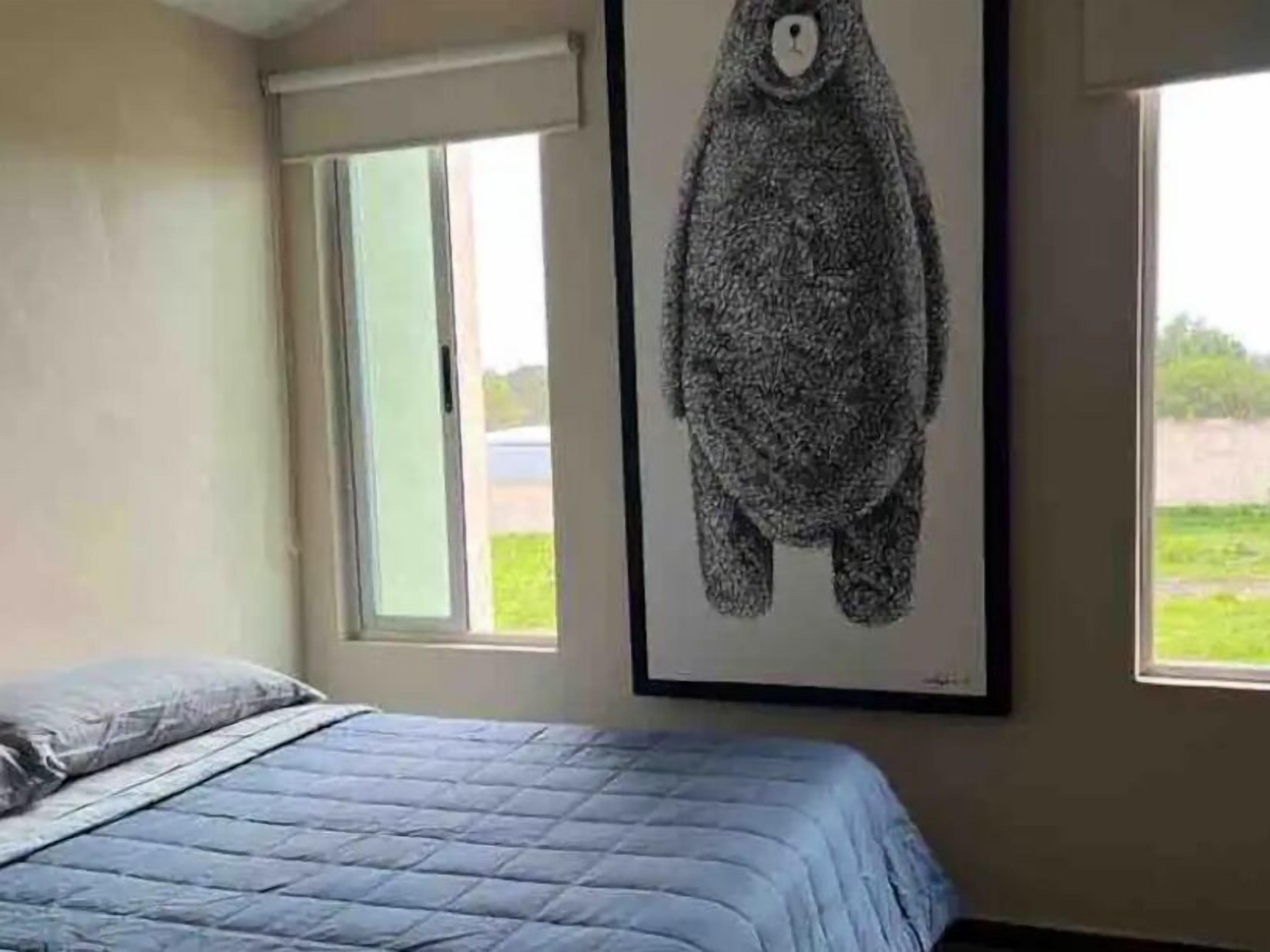 Une chambre à coucher avec un lit, une fenêtre et une œuvre d’art accrochée au mur.