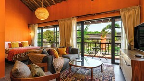 A room with a bed, sofa, and a dining area with a table and chairs. There is a balcony with a view of the outdoors. - Niran Farm (Si Sunthon)
