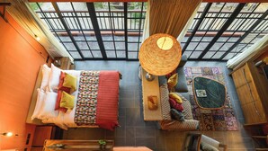 A spacious room with a large bed, a sitting area with a woven chair, and a view through a glass ceiling. - Niran Farm (Si Sunthon)