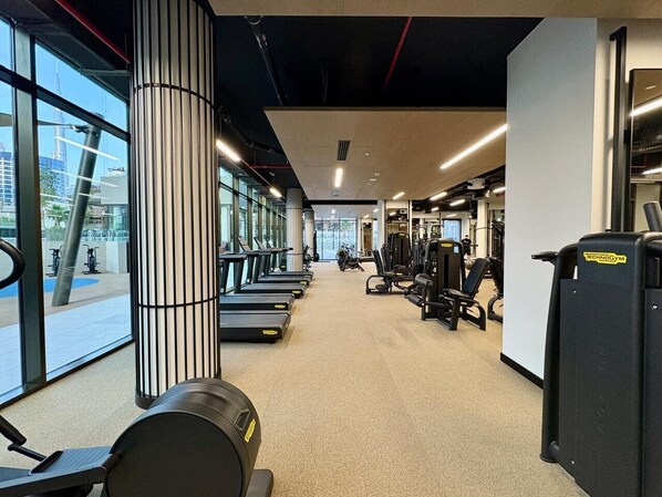 A gym with treadmills, weight machines, and a large pillar.
