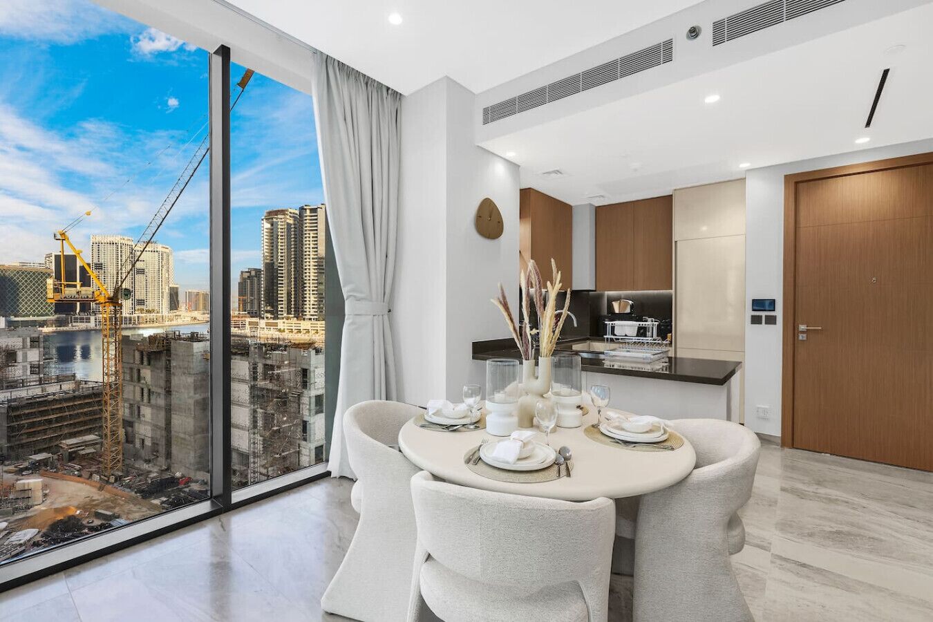 A modern dining area with a city view, a kitchen, and a large window.
