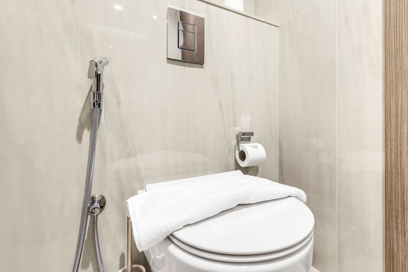 Une salle de bain moderne équipée de toilettes, d’une douche et d’un porte-serviettes.