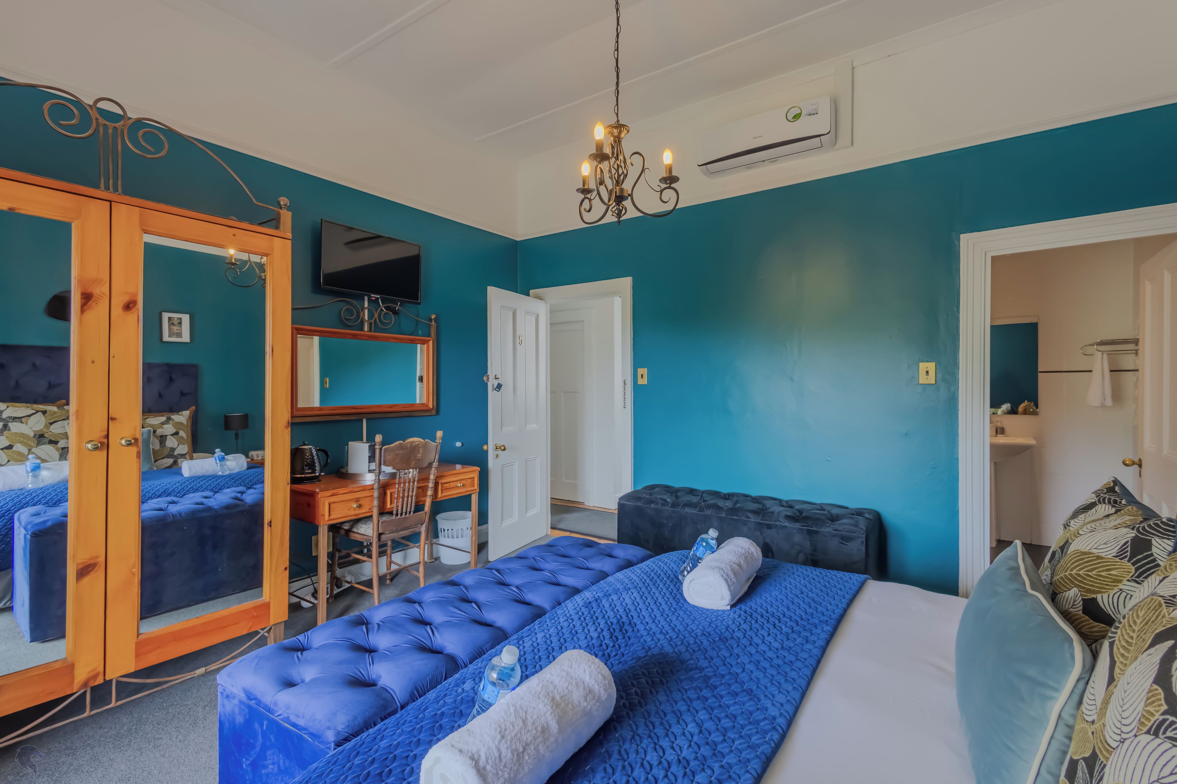 A room with two beds, a desk, a chair, and a television.
