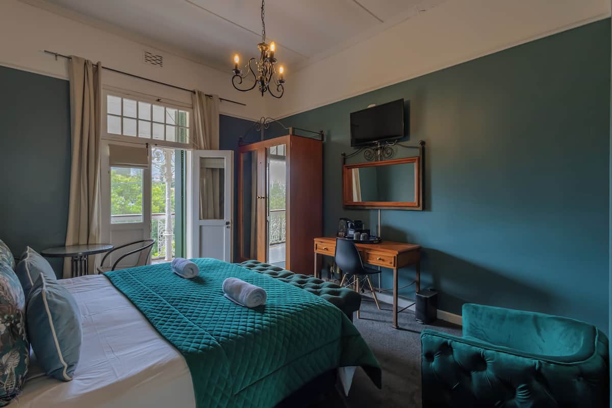 A hotel room with a bed, a desk, a chair, a television, and a window with curtains.