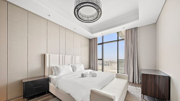 Een moderne hotelkamer met een groot bed, een nachtkastje, een bureau en uitzicht op de stad.