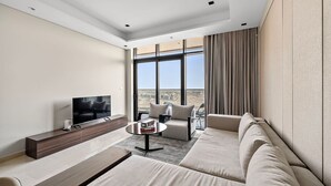Een moderne hotelkamer met een groot raam dat uitzicht biedt op de stad, een flatscreen televisie, een bank, een salontafel en een houten console.