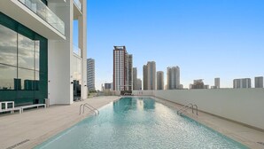 Una piscina en la azotea con vistas despejadas a edificios altos en el fondo.