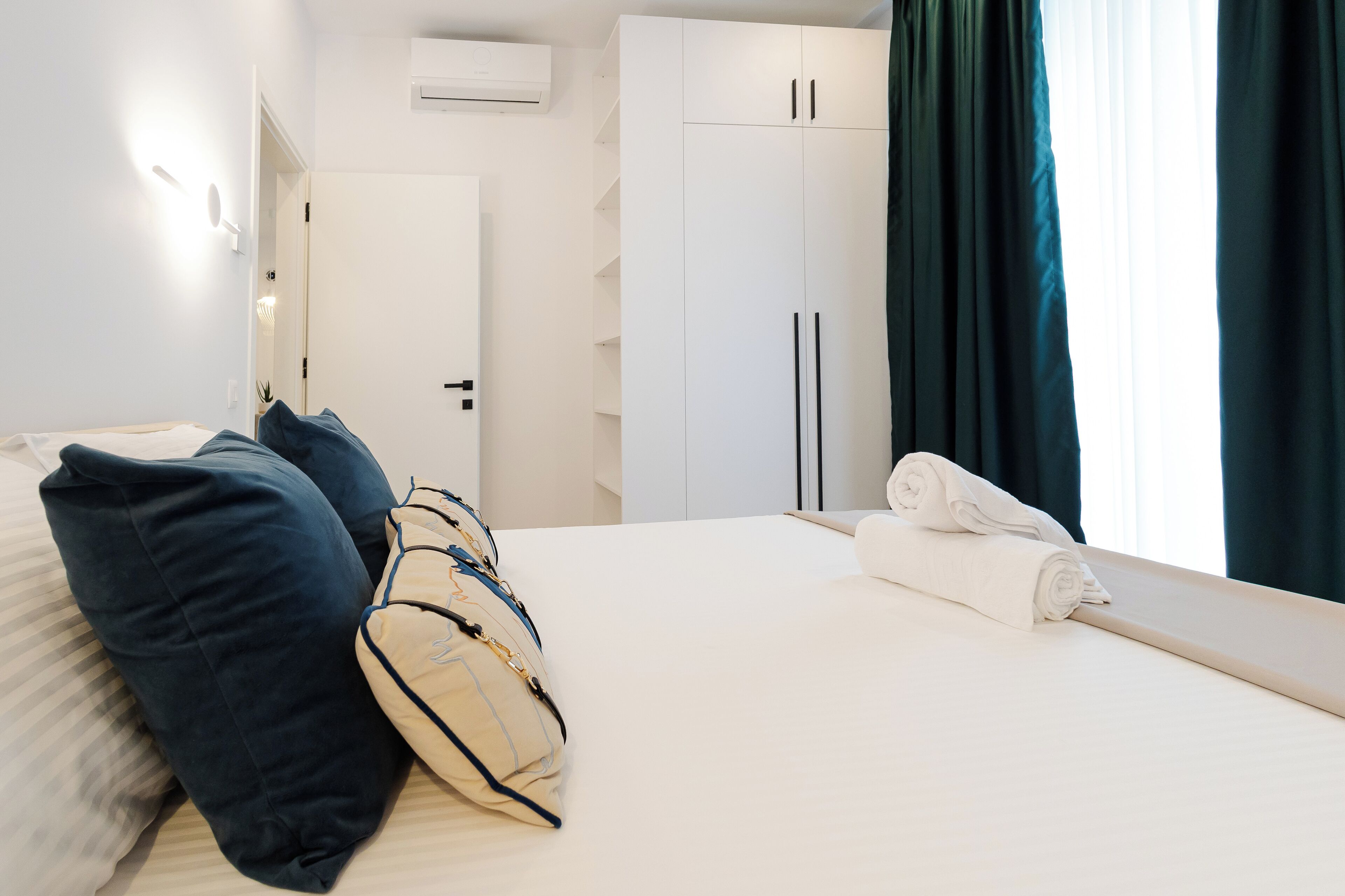 A hotel room with a bed, pillows, a suitcase, and a neatly made bed with a towel.