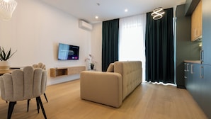 Ein modernes Wohnzimmer mit einer Couch, einem Fernseher und einem Essbereich.
