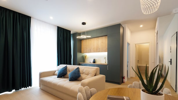 Ein modernes Wohnzimmer mit einem beigefarbenen Sofa, einem Holzesstisch und einer Topfpflanze.