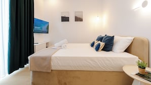 Ein modernes Hotelzimmer mit einem großen Bett, einem an der Wand befestigten Fernseher und zwei gerahmten Bildern.