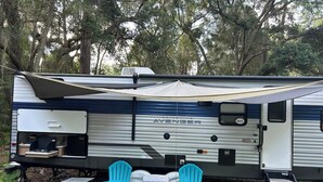 Een camper met een keuken, twee blauwe stoelen en een tafel.