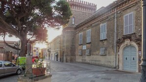 Une rue tranquille bordée de bâtiments historiques, avec une statue et une voiture garée sur le côté.