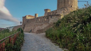Un chemin de pierre mène à un château historique doté d’une tour ronde.
