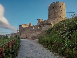 Un sendero de piedra que conduce a un castillo histórico con una torre redonda.