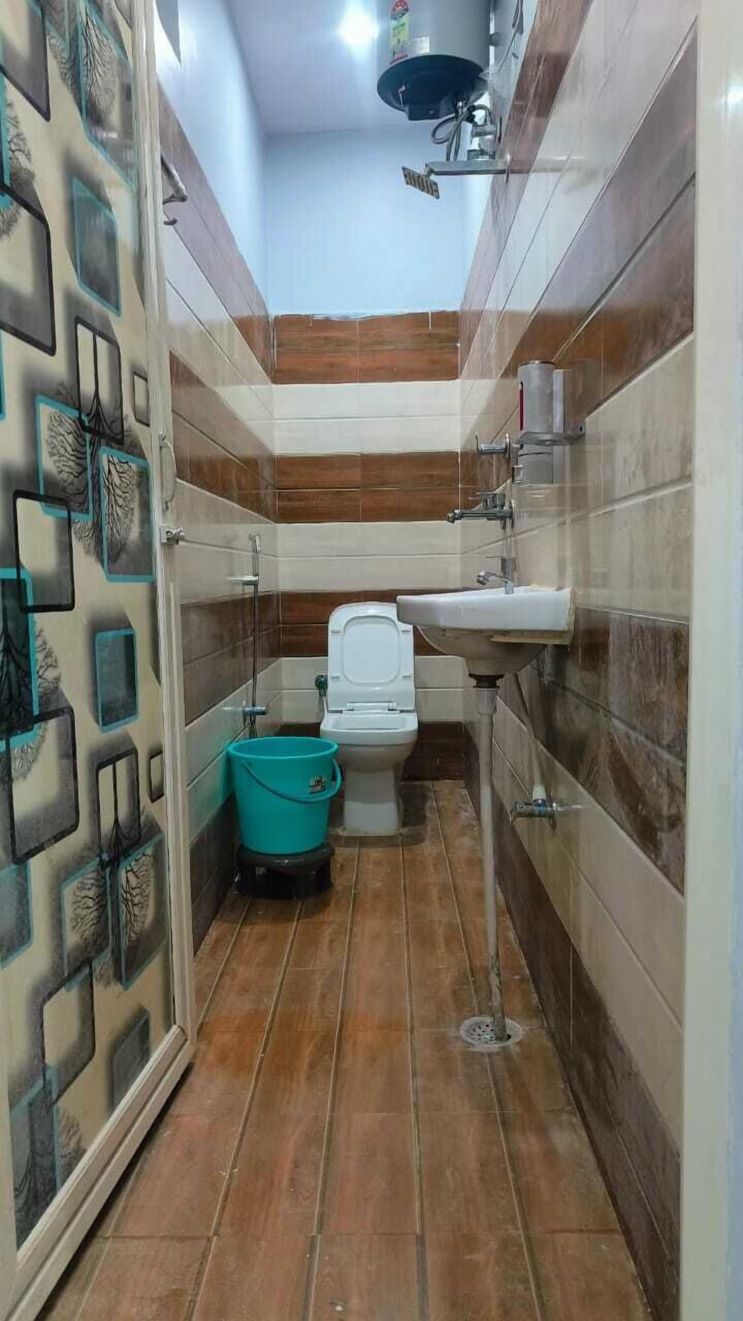 A small bathroom with a toilet, sink, and a blue bucket.