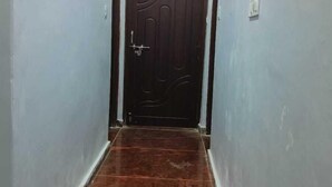 A hallway with a dark wooden floor and light grey walls. - Shivashram Guest House (Varanasi)