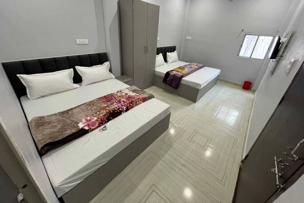A modern bedroom with two beds, a wardrobe, and a window.