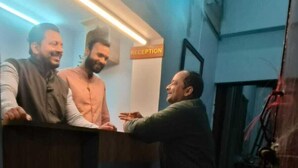 A reception area with a reception desk, a sign indicating 'RECEPTION', and a person standing at the desk. - Shivashram Guest House (Varanasi)