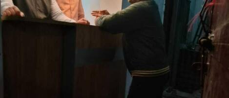 Un'area reception con una scrivania, un cartello con la scritta 'RECEPTION' e una persona in piedi allo sportello.