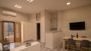 A modern kitchen with a dining area, wooden cabinets, a built-in TV, and a stone lantern on the counter.