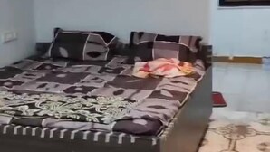 A bedroom with a large bed, a ceiling fan, and a patterned floor.