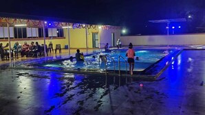 An outdoor swimming pool area at night with people around.
