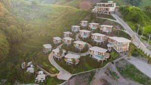 A resort with multiple bungalow-style buildings arranged in a semi-circular layout, surrounded by lush greenery and hills. - Kiri Rhom Khao Kho (Khao Kho)