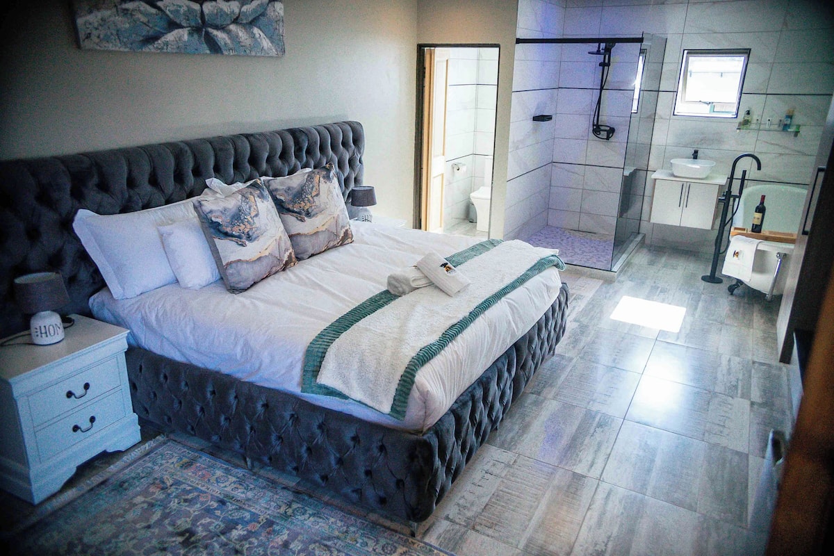 Un dormitorio con una cama grande, una mesita de noche y una mesita auxiliar.
